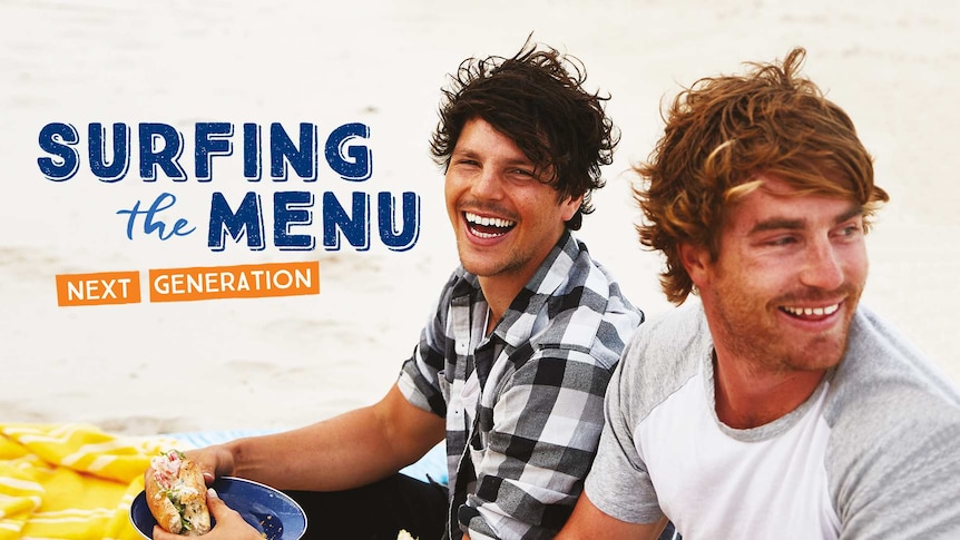 Hosts Dan Churchill and Hayden Quinn eating whilst sitting on beach towels laid on the sand