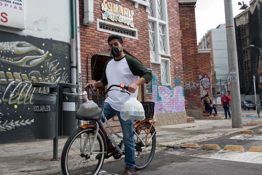 A man on a bike holds white takeaway containers