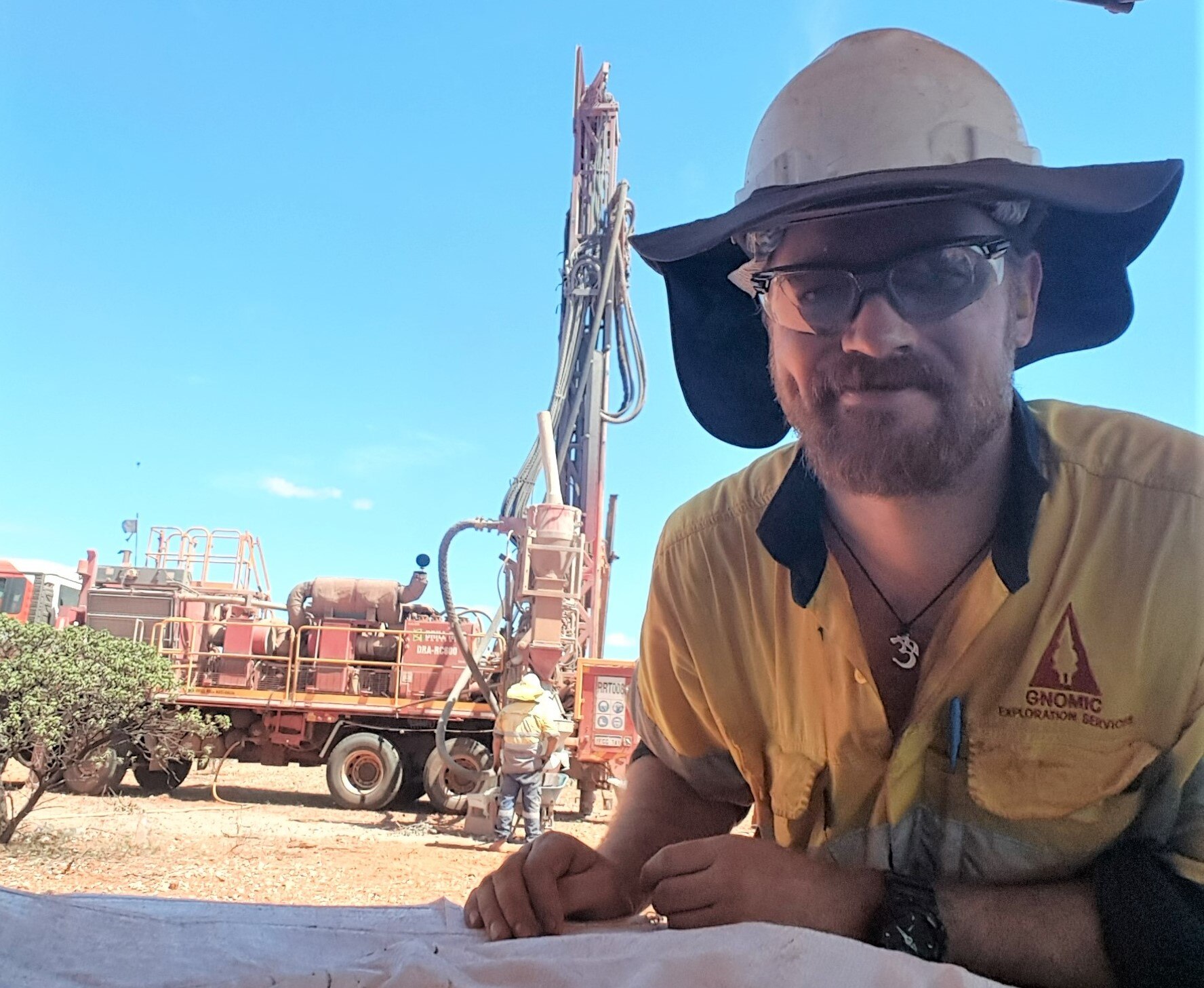 Richard trägt auf einem Erkundungsgelände einen Schutzhelm, eine Schutzbrille und Warnschutz