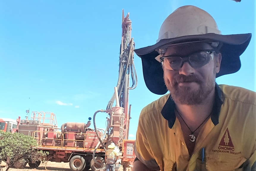 Richard wears a hard hat, safety glasses and high view at an exploration site