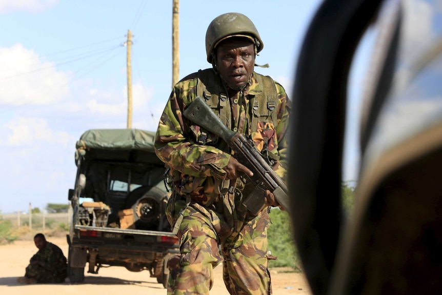 A Kenyan soldier runs for cover near where attackers are holding up a campus in Garissa.
