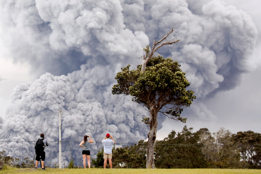 People watch as ash erupts from the Halemaumau crater near the community of Volcano.