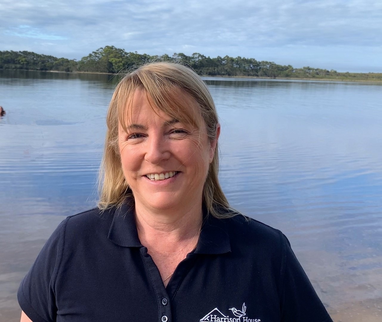 Uma mulher loira em frente a um corpo d'água.
