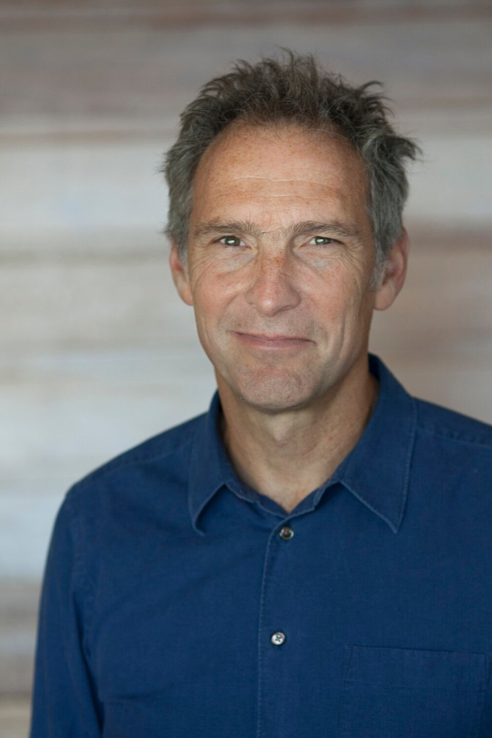 Man wearing blue business shirt smiles.