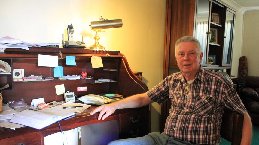 Fay's Twin Cinema owner Don Howard sitting at office desk counting attendance figures.