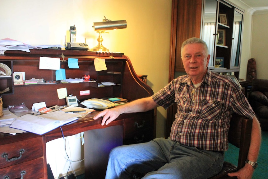 Fay's Twin Cinema owner Don Howard sitting at office desk counting attendance figures.