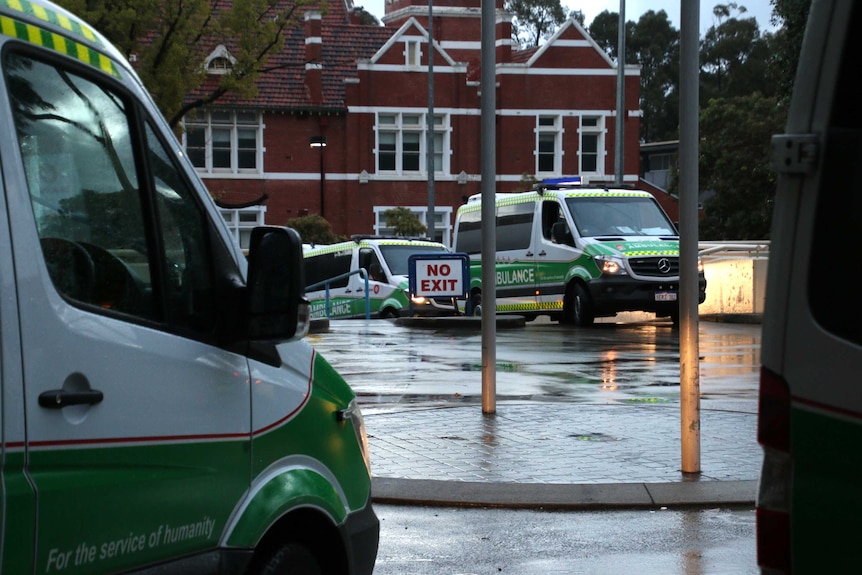 Two ambulances drive off from Princess Margaret Hospital with another ambulance in the foreground.