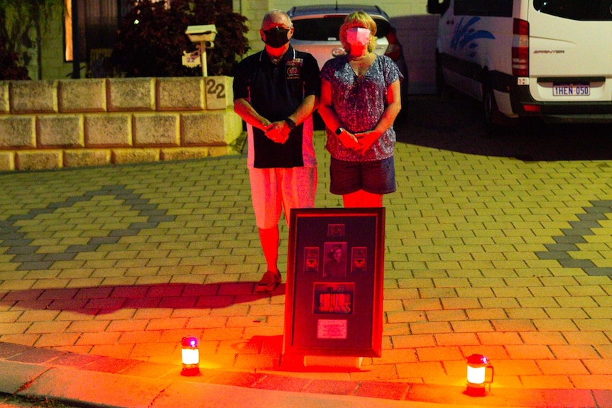 Allan Voak and his wife stand behind a large photo frame and candles.