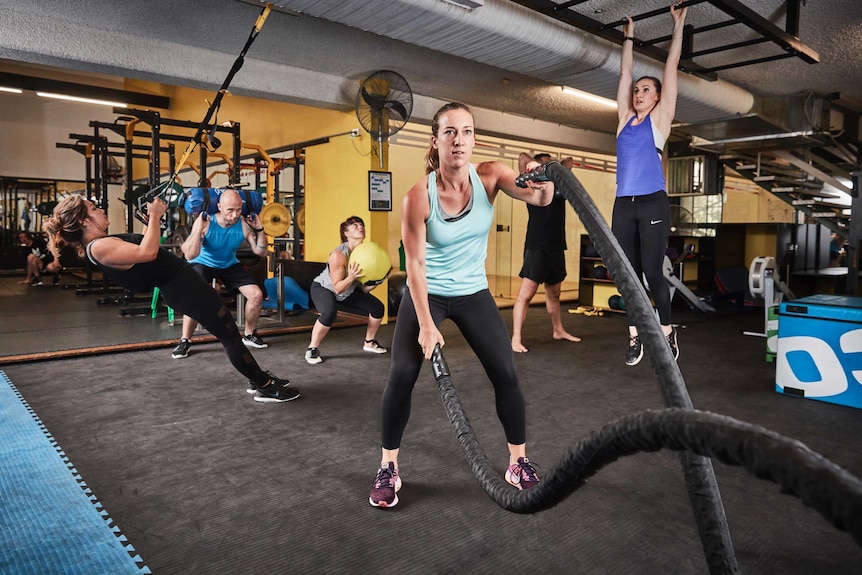 A group of people in fitness wear exercising in a gym.