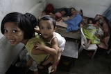 A girl carries her sibling as others sleep in a staircase of an evacuation centre in the Philippines