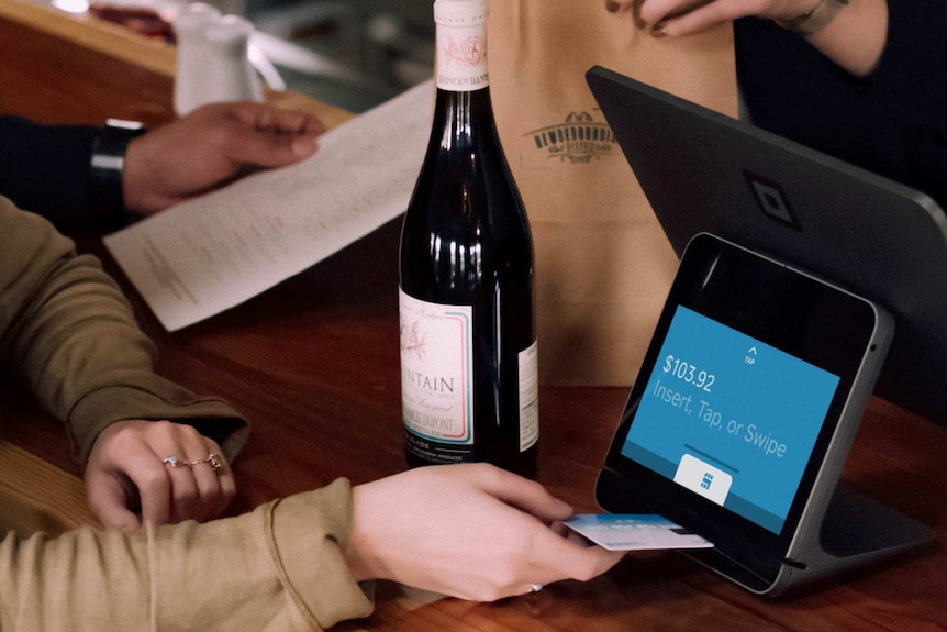 Person using card to buy wine at shop counter