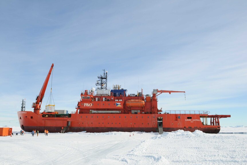 The Aurora Australis icebreaker ship in Antartica surrounded by ice and people.