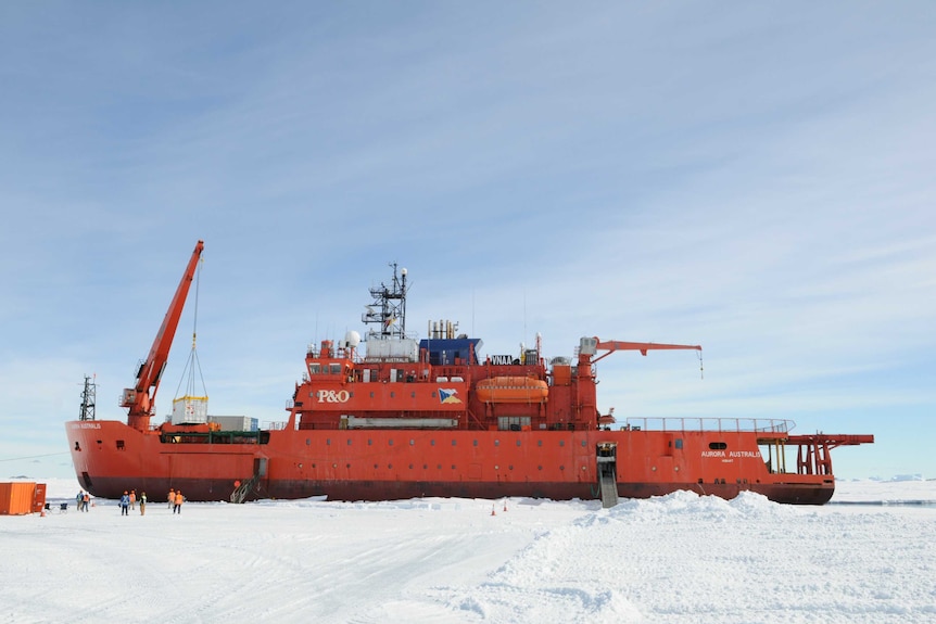 The Aurora Australis icebreaker ship in Antartica surrounded by ice and people.