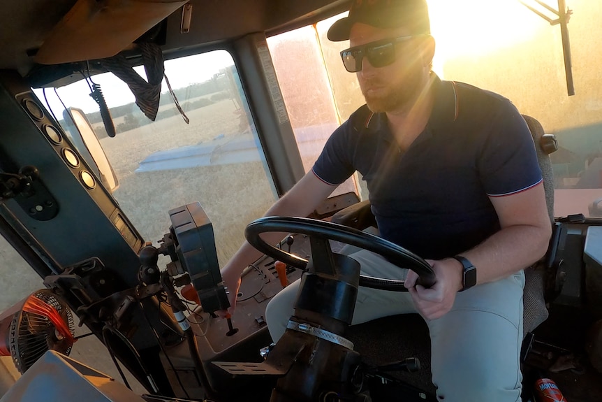   Un homme dans la cabine d'un tracteur bin Chaser lorsque la lumière du soleil sur son épaule.