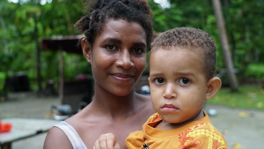 A mother smiles while holding her infant son