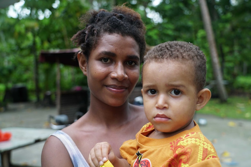 A mother smiles while holding her infant son