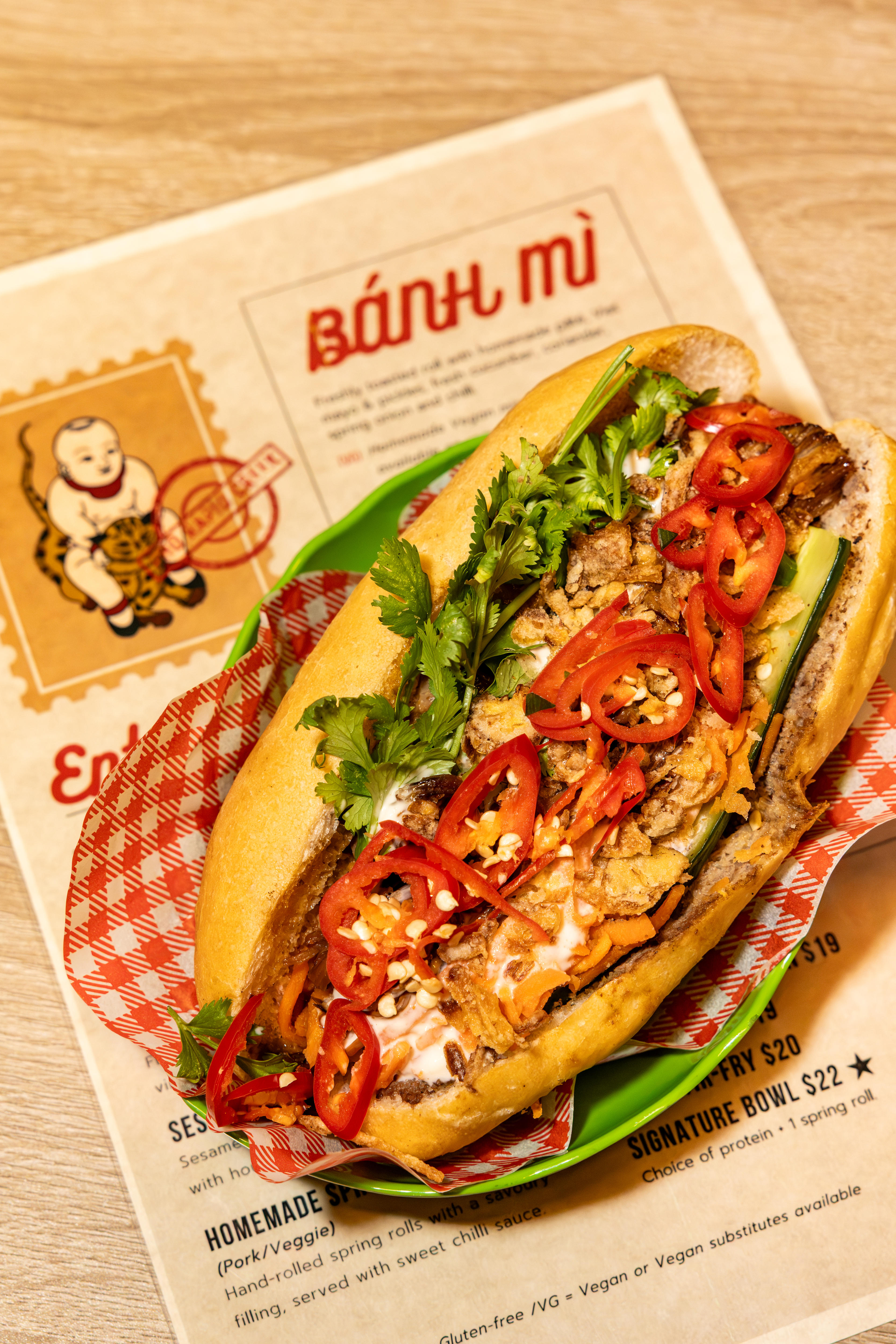 An open banh mi sandwich, which is topped with chilli slices and coriander.