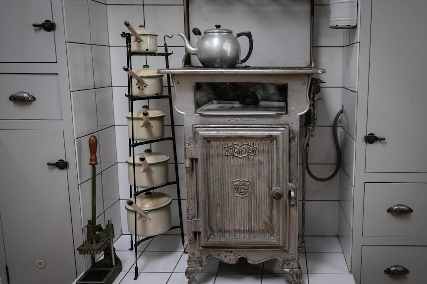 Old fashioned stove with a kettle on top and saucepans stacked alongside.