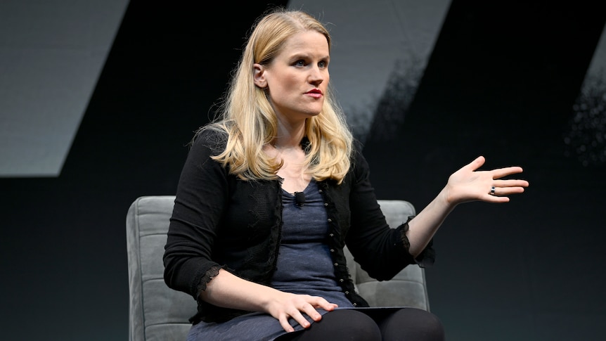 Frances Haugen with blonde hair and dark jumper sits in a chair on stage
