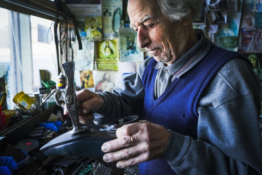 Peter hammers the sole of a boot