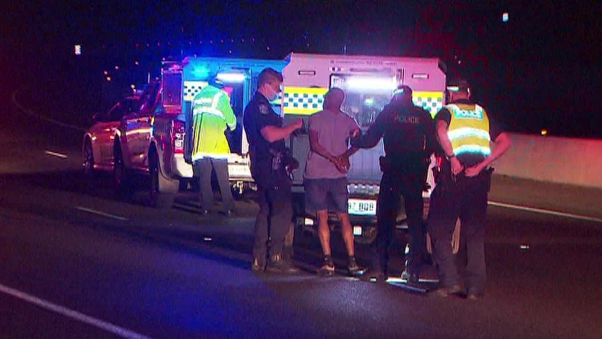 A man is put into a police wagon by several police officers