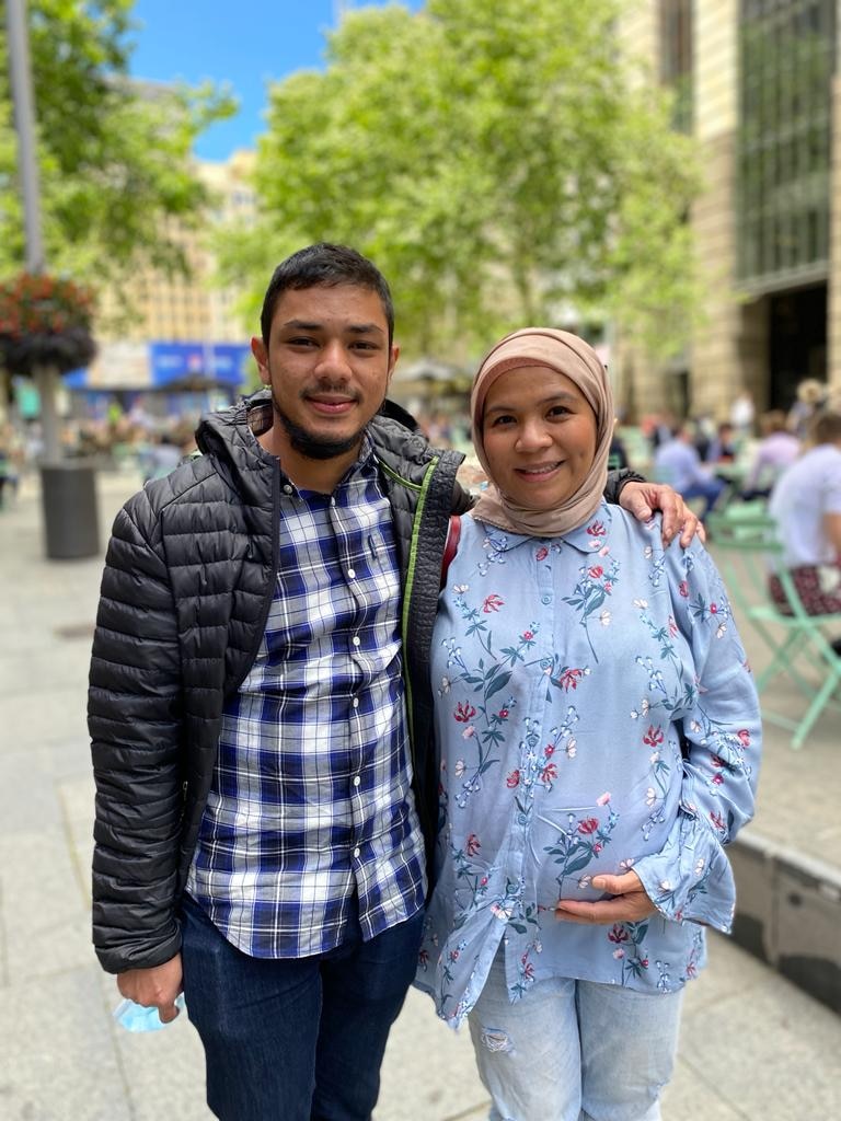 A young Indonesian couple standing with the woman holding her pregnant belly.