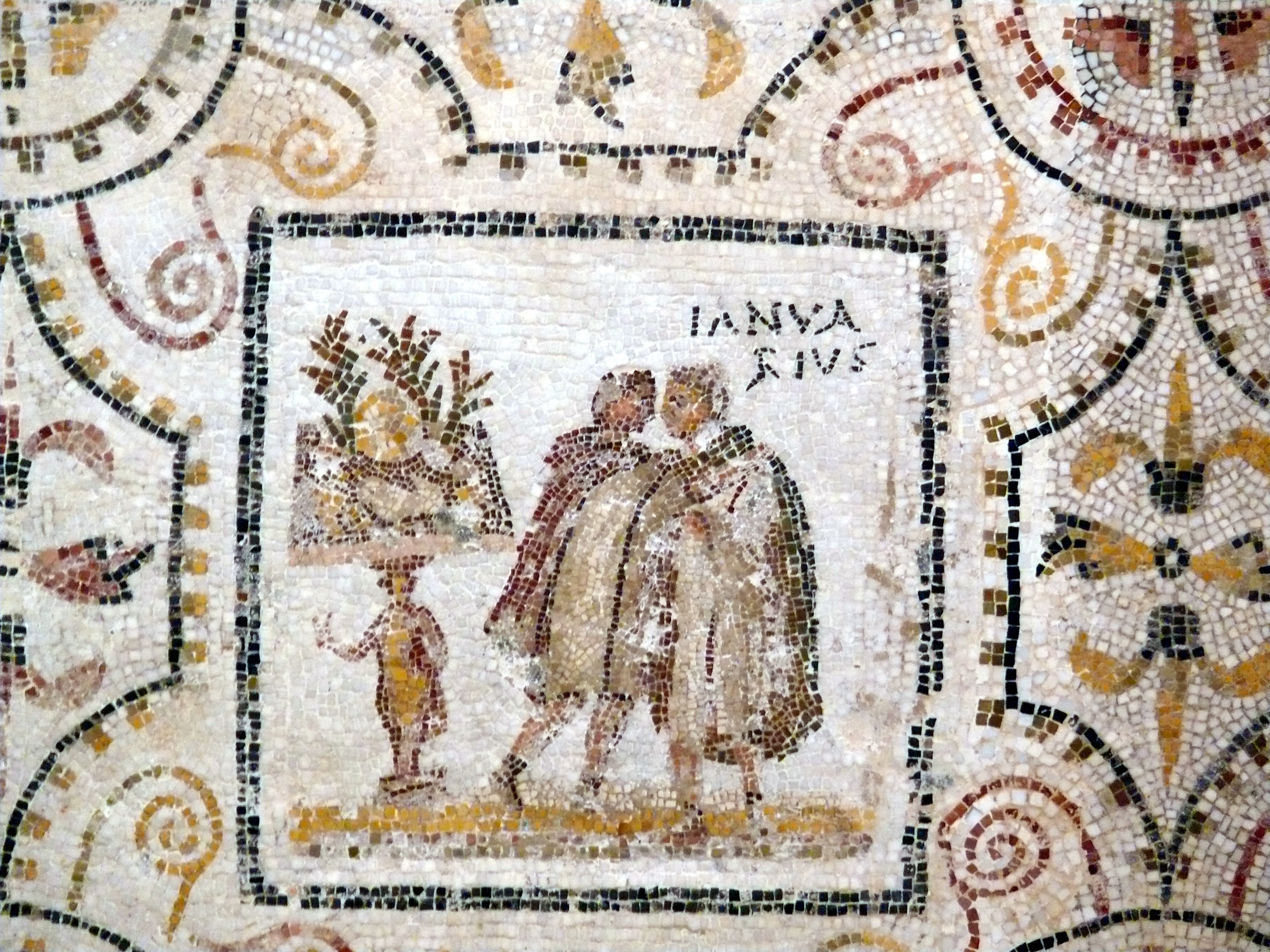 A Roman mosaic showing two men in robes standing next to a table bearing plant decorations, with the inscription 'Ianuarius'.