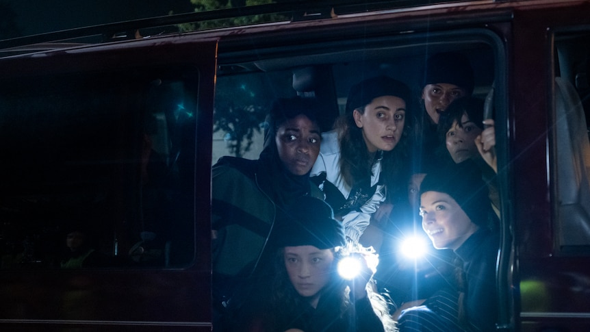 A group of young women in a van, holding torches, in Bottoms.