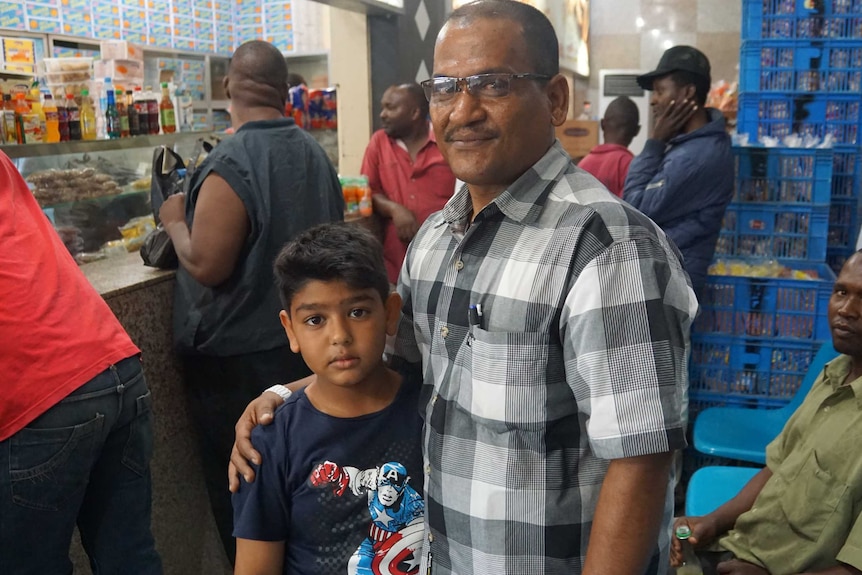 Former heroin addict Abdallah Adwah with his son in a food shop