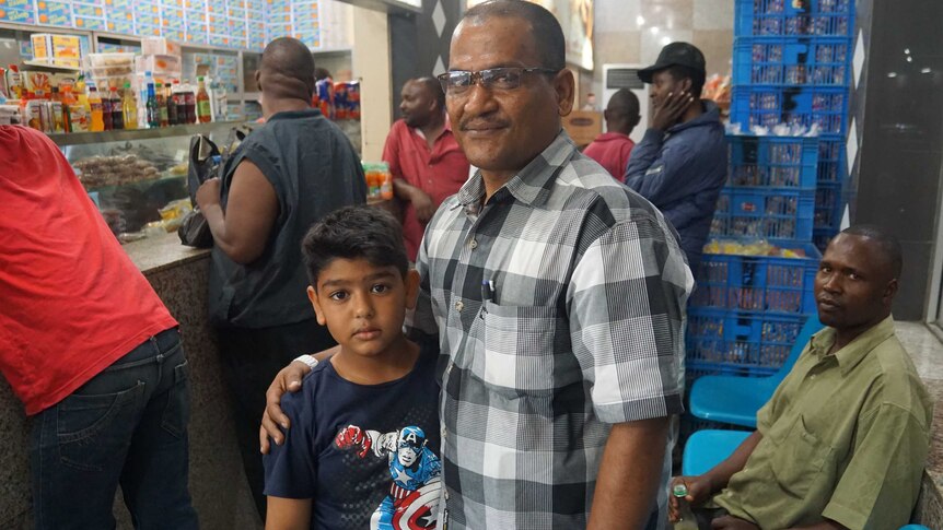 Former heroin addict Abdallah Adwah with his son in a food shop