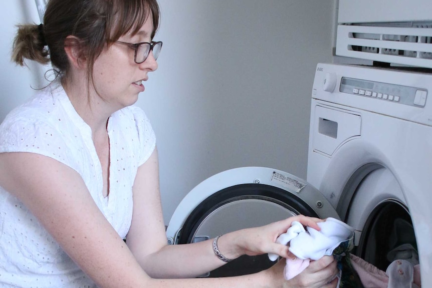 Crystal Wilkes puts clothes in a washing machine