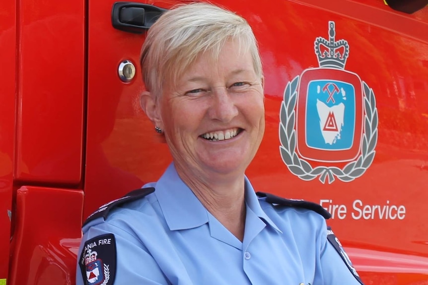 Fiona Tustian wearing a Tasmania Fire Service uniform leans against a fire truck