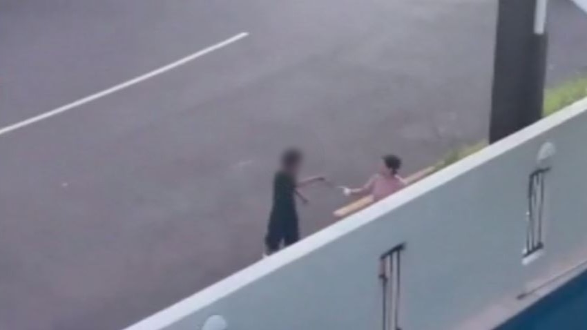 a blurred image of a boy holding a knife to a woman on the street