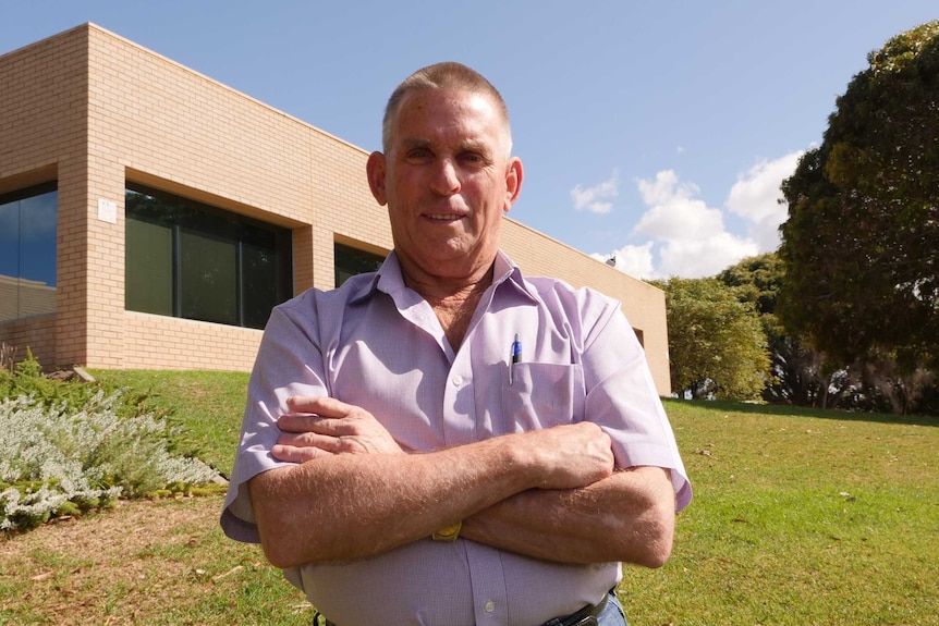 Ian Mickel standing in front of building with arms crossed