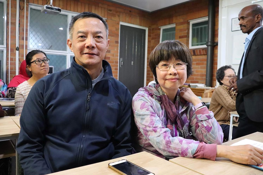 John Fang and Mona Liu sit at a desk together at an English class run by a refugee and migrant service.
