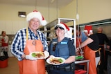 Michael Page and Rose Basford hold roast meal in commercial kitchen,