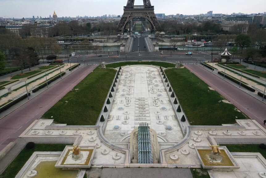 An aerial view shows a usually popular park and promenade empty with the Seine river and Eiffel Tower in the background.