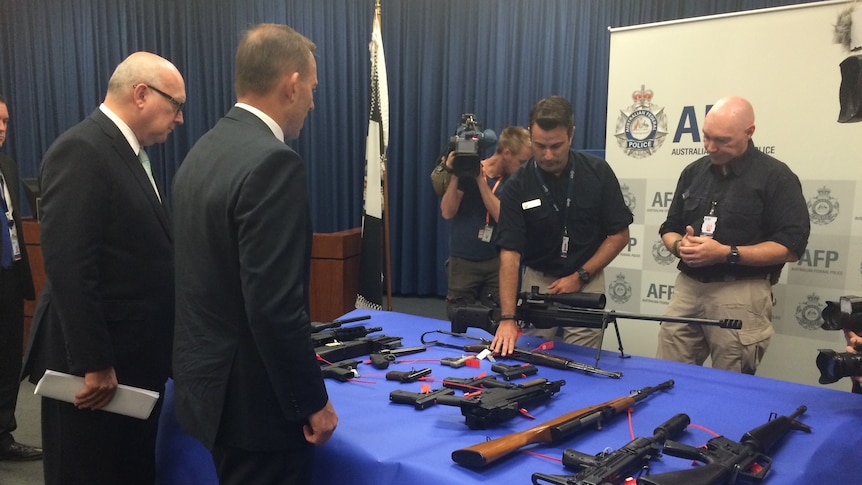 Tony Abbott looks at a table of guns, March 15 2015.