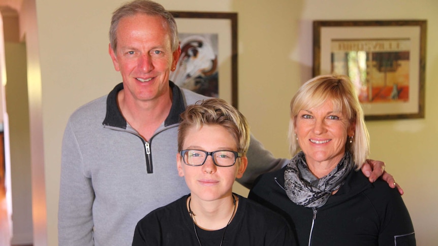 Potrait shot of Leon, 16, and his parents David and Michelle standing inside their house.