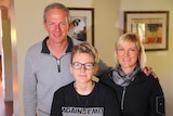 Potrait shot of Leon, 16, and his parents David and Michelle standing inside their house.