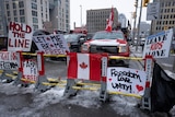 Signs sit on a barricade in front of parked vehicles as part of the trucker protest.