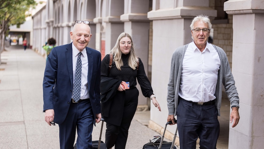 Two men and a woman, all lawyers, walking into a courthouse with briefcases.  