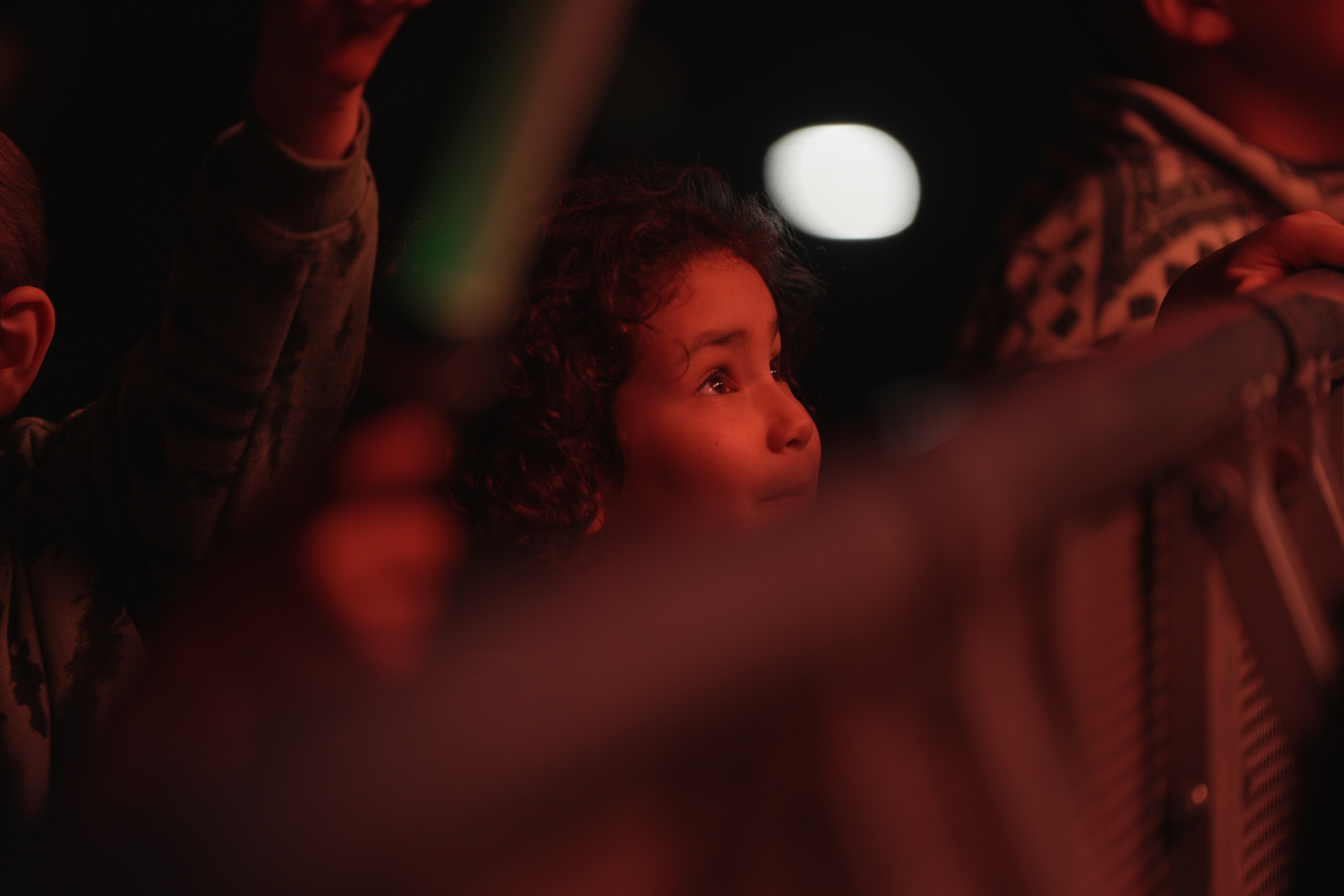 A little girl's face is illuminated by light from the stage.