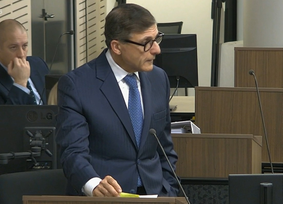 A man wearing thick black frame glasses standing at a podium.