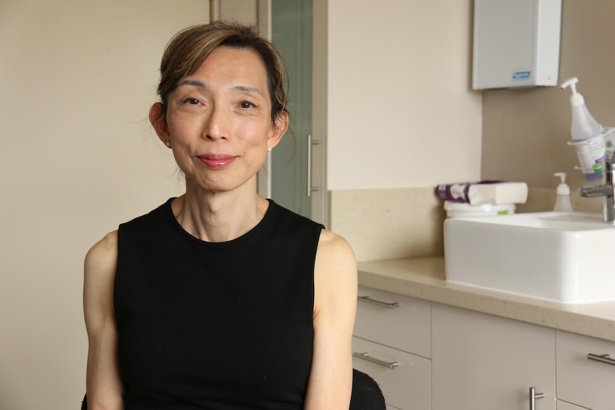 A woman in a black shirt smiles.