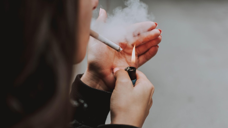 A person lights up a cigarette.