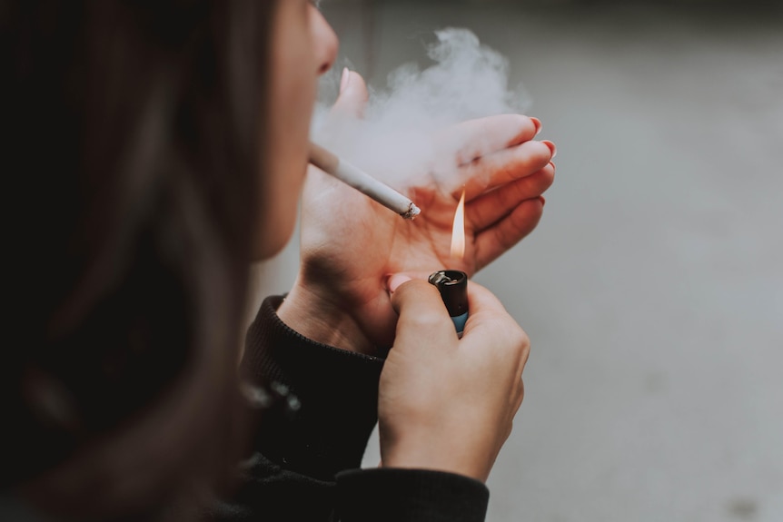 A person lights up a cigarette.