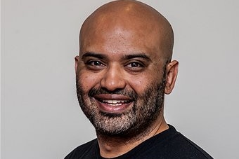 A smiling, bald Indian man.