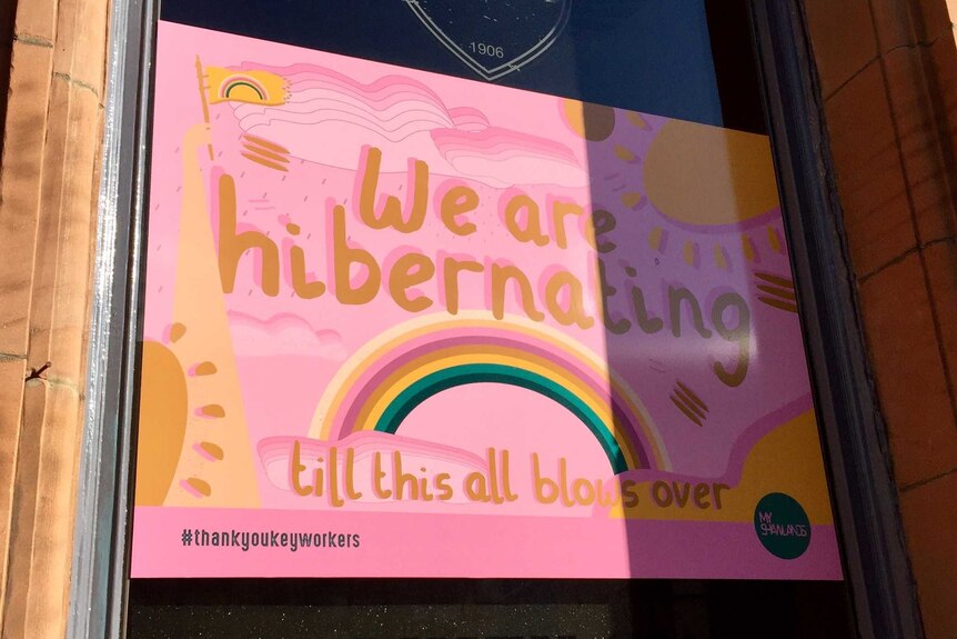 A pink sign on a window saying "We are hibernating"