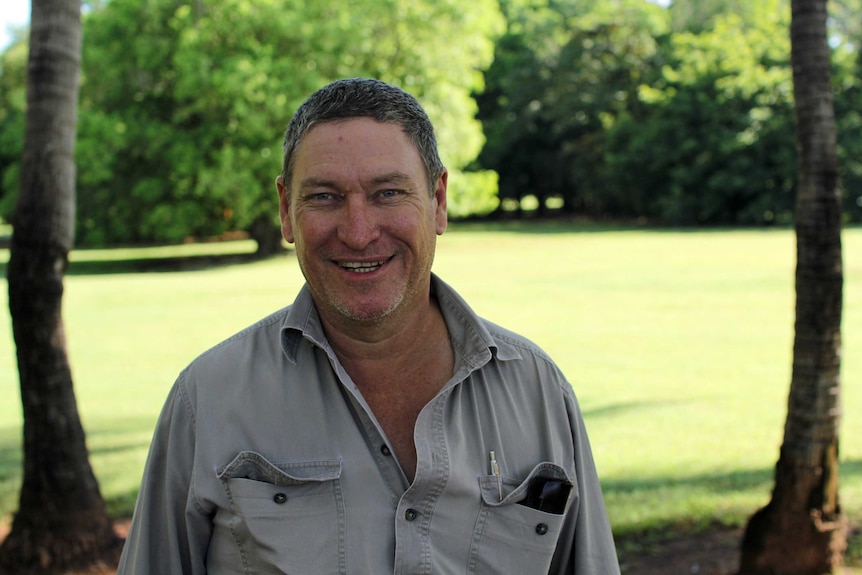 a man next to trees.